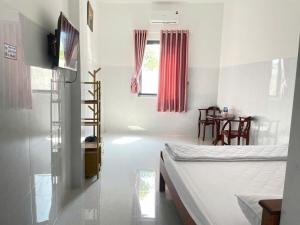 a room with two beds and a table and a television at Khách sạn Thành Châu 3 in Ấp Mỹ Hòa