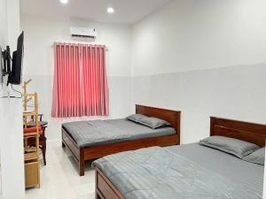 a bedroom with two beds and a red curtain at Khách sạn Thành Châu 3 in Ấp Mỹ Hòa