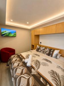 a bedroom with a large bed and a red chair at Suite Casa Mia in Ciudad Sahagún