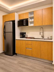 a kitchen with a refrigerator and wooden cabinets at Suite Casa Mia in Ciudad Sahagún
