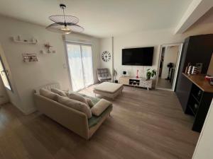 a living room with a couch and a flat screen tv at La Petite Citadine Proche Futuroscope in Poitiers