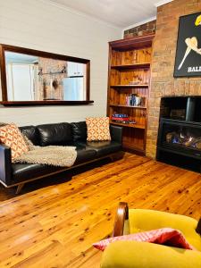 a living room with a black leather couch and a fireplace at Quarryman Cottage @ 102 in Bowral