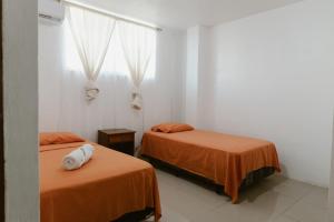 a room with two beds with orange sheets and a window at PELICAN TOURS in Puerto Baquerizo Moreno