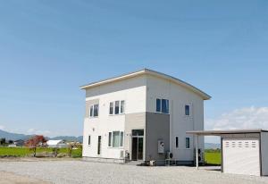a large white building with a garage at ゲストハウス 華園 in Furano