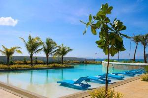 a pool with blue lounge chairs and palm trees at Ciriaco Hotel in Rauis