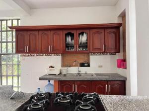 a kitchen with wooden cabinets and a stove top oven at San Gerónimo Casa Hostal in Mocoa