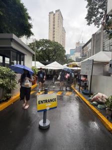 a group of people walking down a street in the rain at The Mosaic Tower in Manila