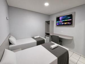 a room with two beds and a tv on the wall at Hotel Colonial Plaza - Ao Lado do Metrô Armênia, 5 Min do Brás e Rua 25 de Março e 10 Min do Expo Pavilhões Anhembi in São Paulo