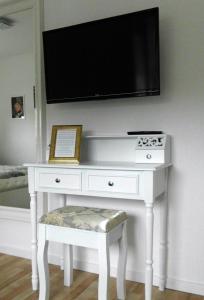 einen weißen Schreibtisch mit einem Flachbild-TV an der Wand in der Unterkunft Villa Regina in Möhnesee
