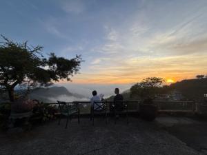 two men sitting at a table watching the sunset at 傳說民宿 Legend in Fenqihu +9 photos