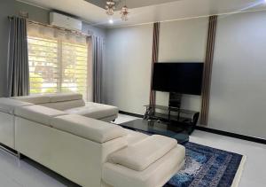 a living room with a white couch and a flat screen tv at Pizzaro Flats 2 in Chongwe