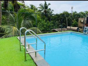 a swimming pool with blue water and some trees and a fence at Sevrina Beach Inn Calangute in Calangute