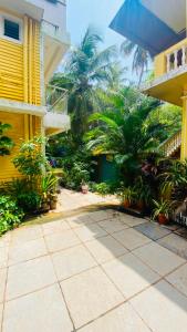 a courtyard with palm trees and a yellow building at Sevrina Beach Inn Calangute in Calangute