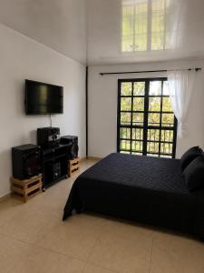 a bedroom with a bed and a flat screen tv at Finca Cabañas el Higueron in Nocaima
