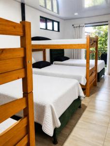 a bedroom with three bunk beds with white sheets at Finca Cabañas el Higueron in Nocaima