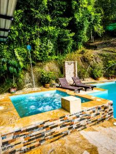 a swimming pool with two chairs and a table at Finca Cabañas el Higueron in Nocaima