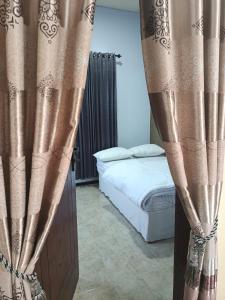 a bedroom with a bed and some curtains at River cliff guest house in Gunungsriti