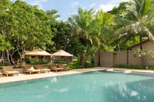 a swimming pool with chairs and umbrellas and trees at Hidden Secrets Dambulla in Dambulla
