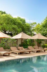 a group of chairs and umbrellas next to a pool at Hidden Secrets Dambulla in Dambulla