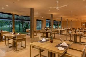 a restaurant with wooden tables and chairs and windows at Hidden Secrets Dambulla in Dambulla