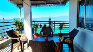 a table and chairs on a balcony with a view at Greenview108 in Kurseong +4 photos