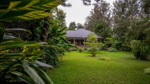 a garden with a house in the background at Maksoru Spring Lodge in Arusha