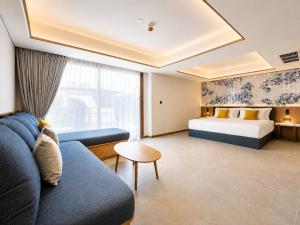 a hotel room with a couch and a bed at Myneris Hotel, Phuket Karon Beach in Karon Beach