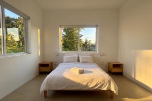a bedroom with a white bed with two windows at Villa Leo in Ban Madua Wan