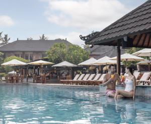 two people sitting in the water at a swimming pool at Private 2BR Apartment at The Jayakarta Residence Bali in Denpasar