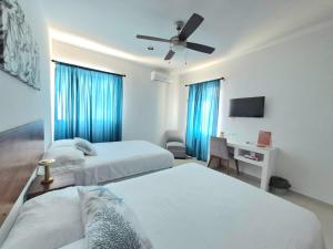 a bedroom with two beds and a ceiling fan at Casa Terracota Micro Hotel Consulado in Mérida