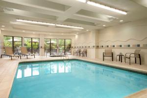 a swimming pool with chairs and tables in a building at Courtyard by Marriott Middletown Goshen in Middletown