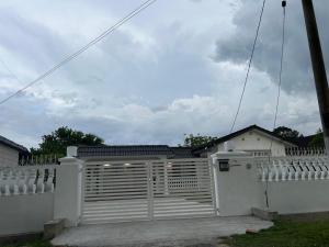 a white fence with a gate in front of a house at Haus176 in Bentong