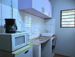 a small kitchen with a sink and a microwave at Maison fleurie Ouidah in Ouidah