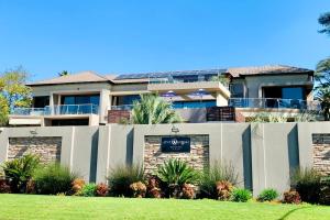 a house with a sign in front of a fence at One O Eight Boutique Hotel in Benoni