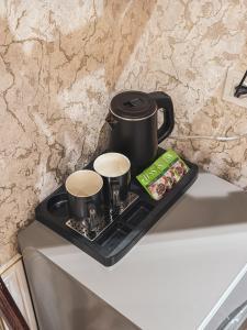 a black tray with two coffee cups on top of a refrigerator at As-Mira Hotel in Samarkand