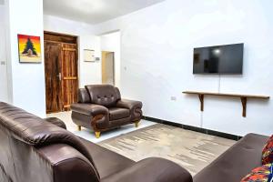 a living room with two leather chairs and a flat screen tv at Ocean-View Balcony - Uroa 2 bedroom Beachfront apt in Uroa