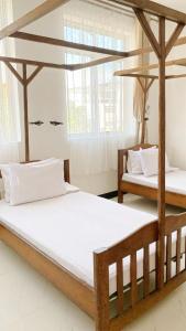 two beds in a room with white sheets at Ocean-View Balcony - Uroa 2 bedroom Beachfront apt in Uroa