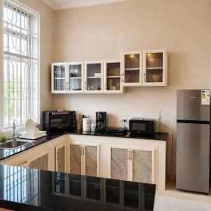 a kitchen with white cabinets and a stainless steel refrigerator at Ocean-View Balcony - Uroa 2 bedroom Beachfront apt in Uroa