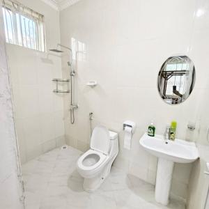 a white bathroom with a toilet and a sink at Ocean-View Balcony - Uroa 2 bedroom Beachfront apt in Uroa +25 photos