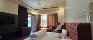 a man sitting on a bed in a hotel room at Parinay Pavilion LLP in Bahraich