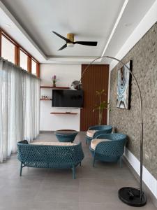 a living room with blue chairs and a tv at Bella Napoli Resort & Resto in Panglao Island