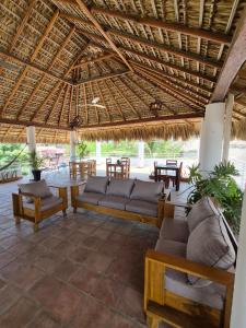 a patio with couches and tables and a straw roof at Sicarú, La Punta - Puerto Escondido in Brisas de Zicatela