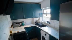 a kitchen with blue cabinets and a washing machine at Luxurious Modern Town House in Gillingham