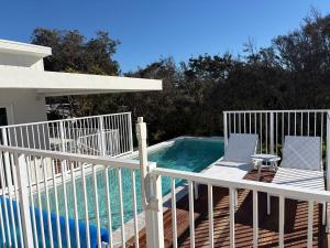 a pool with two chairs next to a white fence at Tiberius House in Saint Andrews Beach