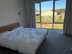 a bedroom with a bed and a large window at Tiberius House in Saint Andrews Beach