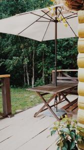 a picnic table with an umbrella and a bench at Härjamäe Saunamaja 