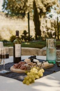 a bottle of wine next to a plate of food and grapes at Maison Meraka - Design Guest House of Saint Emilion in Saint-Laurent-des-Combes