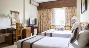 a hotel room with two beds and a desk and a television at Saigon Star Hotel in Ho Chi Minh City