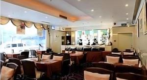 a restaurant with tables and chairs in a room at Hedong Hotel in Shenzhen