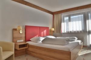 a bedroom with a bed with a red headboard and a window at Hotel Moawirt in Wagrain